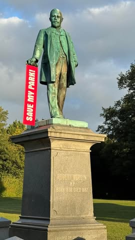 The Robert Verdin statue holding a red 'Save My Park!' placard