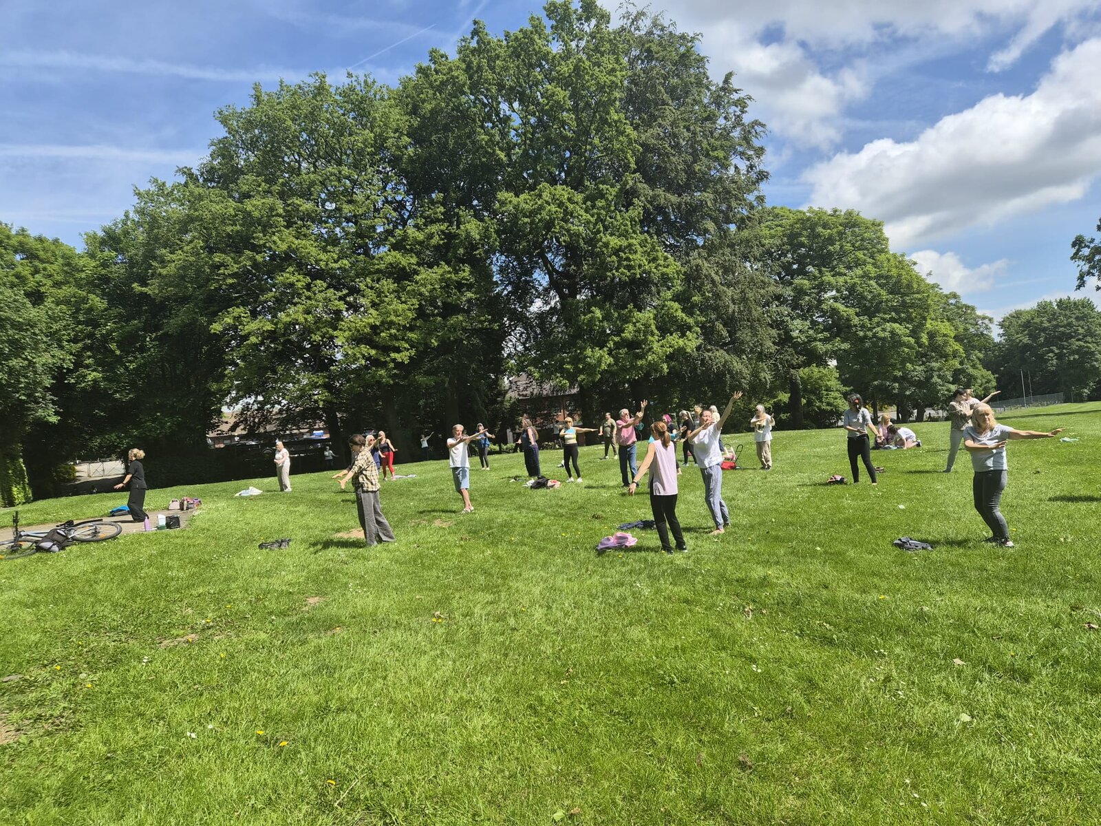 Participants practising Tai Chi on the open south lawn of Verdin Park on a sunny May morning