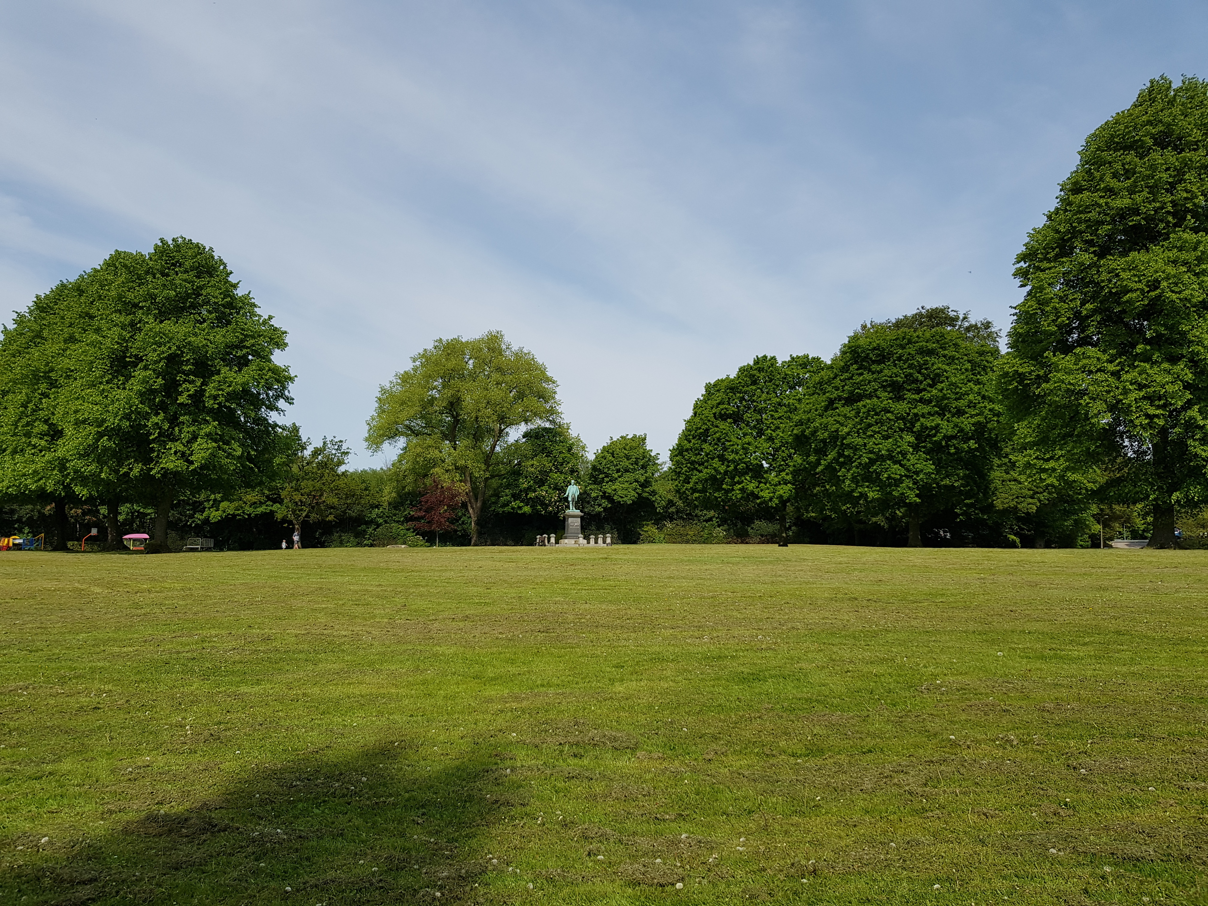 Wide view across the lower lawn of Verdin Park with the memorial statue visible in the distance